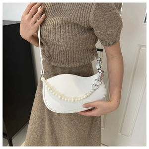 Detail of white wave shoulder bag with pearl chain and silver heart charms on model