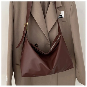 Detail of minimalist dark brown PU leather tote with gold buckle and smooth top zipper