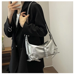 Détail du sac à bandoulière argenté métallisé avec boucles et anneaux sur blazer noir