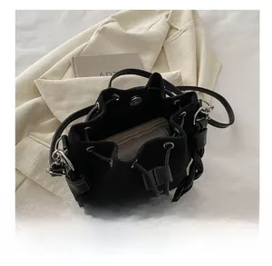 Détail du sac seau en daim noir avec poignée tressée et grande capacité intérieure