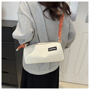 Detail of white corduroy cylinder bag with orange woven rope strap and fashion label