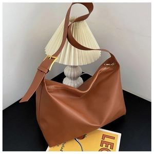 Close-up of brown matte leather hobo bag with adjustable strap and gold metal buckle