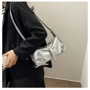 Close-up of a silver shoulder bag with metallic buckle straps and pleated texture detail