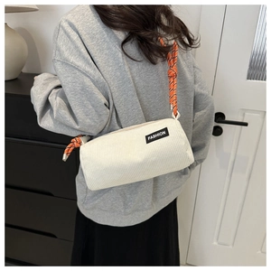 Detail of white corduroy cylinder crossbody bag with orange woven rope strap and logo patch