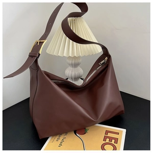 Detail of dark brown leather tote bag with wide adjustable strap and golden metal buckle