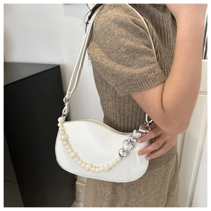 Close-up of white crescent shoulder bag with pearl chain and silver heart hardware