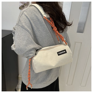 Detail of cream corduroy cylinder bag with FASHION label and orange braided strap