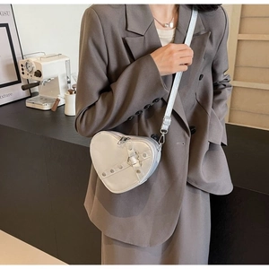 Close-up of heart-shaped silver crossbody bag with metallic studs on a female model