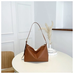 Detail view of large brown hobo bag with gold metal buckle on minimalist white table
