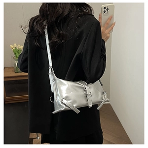 Detail view of metallic silver shoulder bag with buckle straps on a black blazer