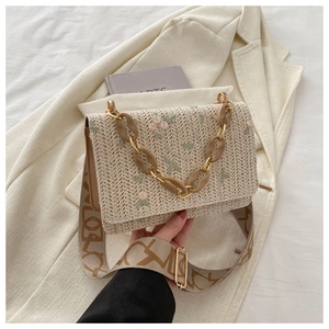 Detail of straw woven bag with floral embroidery and textured resin chain strap