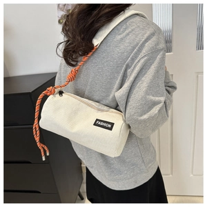 Detail of off-white corduroy cylindrical bag with orange woven rope shoulder strap