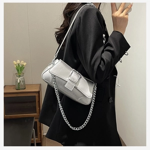 Close-up of silver baguette bag with metallic chain strap and square buckle detail