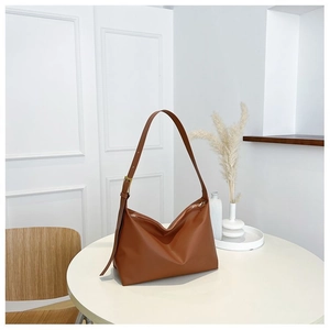 Detailed view of caramel leather hobo bag with adjustable strap on white table