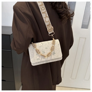 Detail of embroidered straw crossbody bag with wide shoulder strap and resin chain link