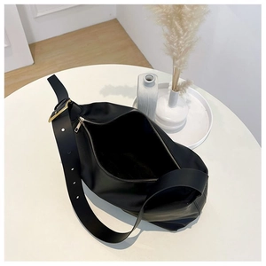 Top view of large black leather hobo bag with gold hardware on a minimalist table