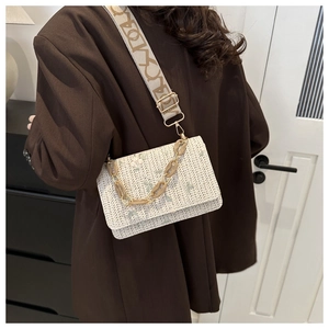 Rear view of a model wearing the white woven straw bag with green floral embroidery