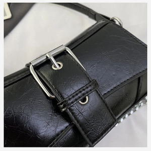 Detail of black vintage shoulder bag featuring oily wrinkled texture and silver buckle