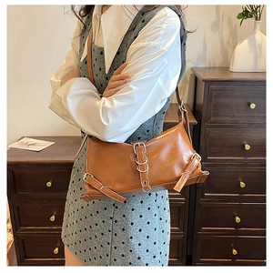 Gros plan du sac à bandoulière marron avec boucle en métal et détails d'anneaux