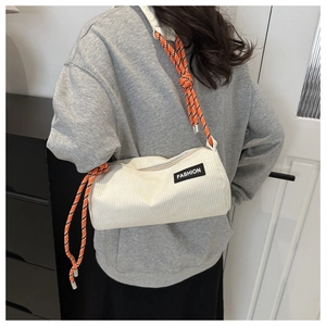 Detail of white corduroy cylinder bag with orange woven strap and Fashion label