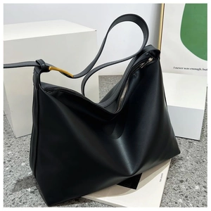 Detail of soft matte black tote bag with silver zipper and golden metal buckle