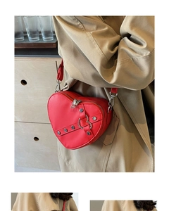 Detail of red heart-shaped PU leather crossbody bag with metallic buckle on a model
