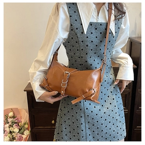 Sac bandoulière marron vintage avec boucles porté avec une robe à pois élégante
