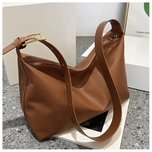 Detail of adjustable strap with gold triangular metal buckle on brown hobo shoulder bag