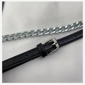 Detail of black leather shoulder strap with silver metal buckle and cuban chain texture