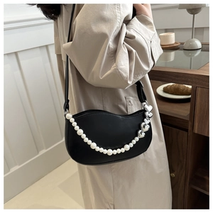 Detail of black crescent shoulder bag with pearl chain and heart-shaped metal buckle
