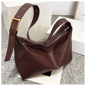 Detail of dark brown leather tote bag with wide strap and large gold metal buckle