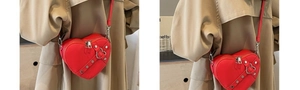 Detail of red heart-shaped crossbody bag with silver rivets and adjustable strap