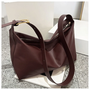 Detail of burgundy leather shoulder bag showing adjustable strap with gold metal buckle