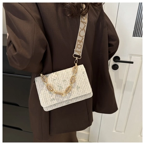 Detail of straw shoulder bag with floral embroidery and amber resin chain strap