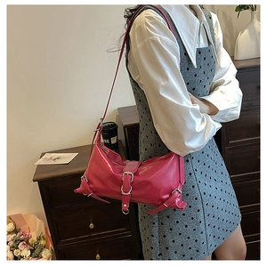 Détail du sac bandoulière en cuir rose vif avec boucles argentées et style punk