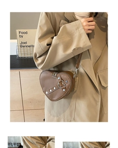 Detail view of heart-shaped crossbody bag with silver rivets and metal ring clasp