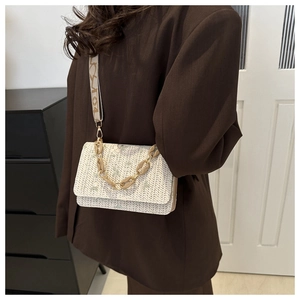 Detail of woven beige crossbody bag with floral embroidery and gold chain strap