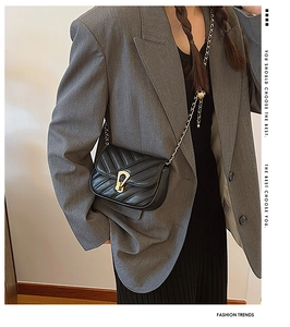 Détail du sac à bandoulière matelassé noir avec fermoir fer à cheval doré et chaîne