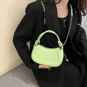 Lime green leather shoulder bag with silver chain strap worn by model in black suit