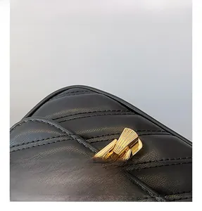 Détail du fermoir doré sur le sac à bandoulière en cuir noir avec surpiqûres