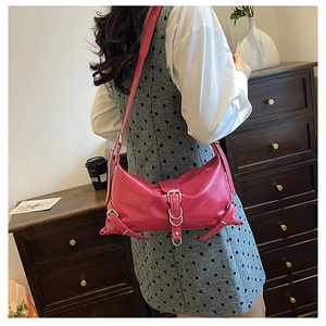 Detail of trendy rose red shoulder bag with glossy leather and metallic silver buckles
