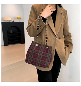 Detail of plaid wool bucket bag with gold chain strap on a chic minimalist blazer