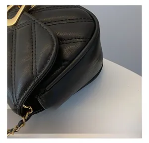 Détail du sac selle en cuir matelassé montrant le fermoir doré en forme de D