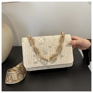 Detail of straw woven bag with floral embroidery, acrylic chain and patterned strap