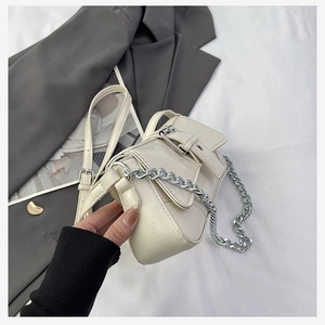 Detail of cream pleated bag featuring bold silver buckle and chunky metal chain strap