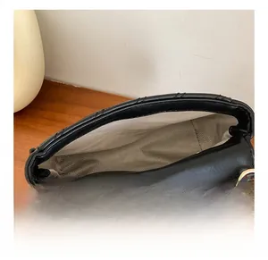 Gros plan du sac bandoulière noir montrant l'intérieur spacieux et la doublure grise