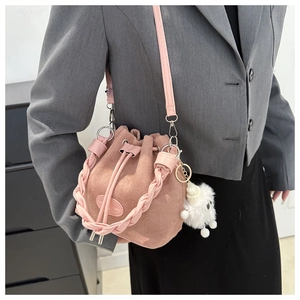 Sac seau rose en daim avec poignée tressée et pompon sur une veste de blazer grise