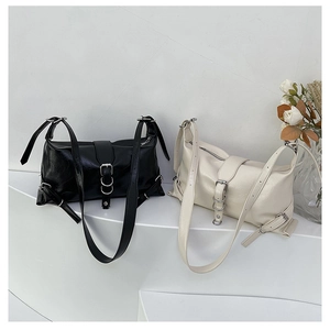 Sacs à bandoulière chics noir et beige sur un présentoir blanc avec des roses