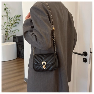 Gros plan d'un petit sac carré noir matelassé en V avec chaîne et fermoir dorés