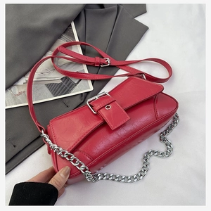 Detailed view of red crinkled patent leather crossbody bag with silver chain and buckle